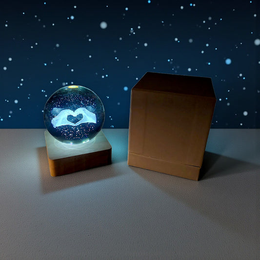 Sfera di cristallo luminosa con base in legno in tema mani a forma di cuore