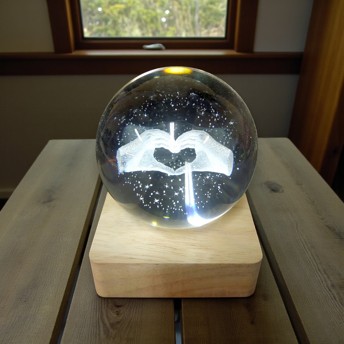 Sfera di cristallo luminosa con base in legno in tema mani a forma di cuore
